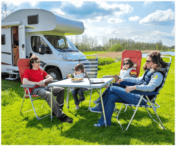 A group of people sitting around an rv.